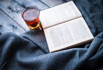 Tea, book and blanket on a wooden background
