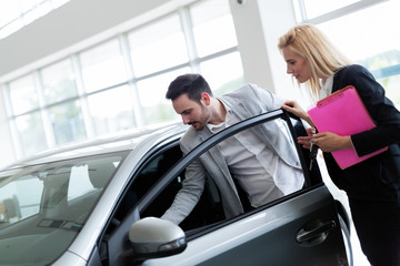 Fototapeta na wymiar Professional salesperson selling cars at dealership to buyer