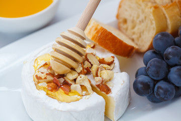 Brie cheese (camembert) with honey, nuts, baguette and fruit