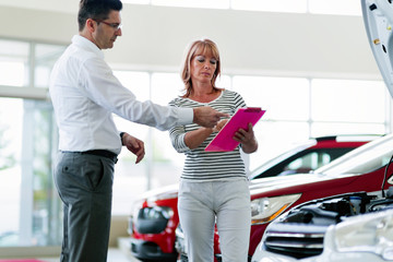 Professional salesperson selling cars at dealership to buyer