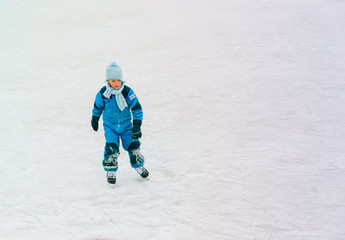 Fototapeta na wymiar little boy skating on ice in winter