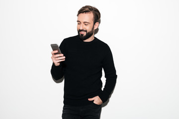 Portrait of a smiling bearded man texting on mobile phone