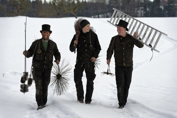 Three laughing chimney sweeps walking in snow