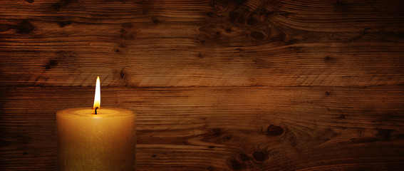Fototapeta na wymiar Burning candle in front of rustic wooden wall