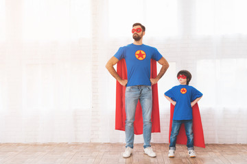 Father and son in the red and blue suits of superheroes. On their faces are masks and they are in raincoats.