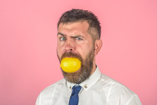 Man with long beard eat lemon.
