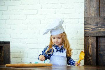 Boy cook in chef hat and apron in kitchen