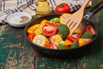 Fresh fruits and vegetables on a frying pan on an old wood background