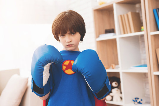 A little dark-haired boy in a superhero shirt. He poses in boxing gloves