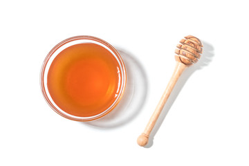 Honey dipper and honey in jar on white background.