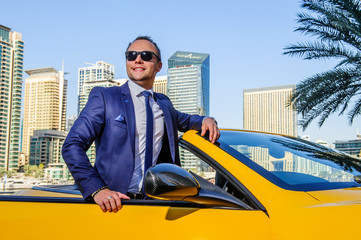 Successful yang businessman in yellow cabrio car.Dubai,UAE.