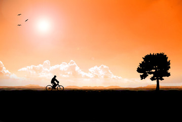 Silhouette Man are cycling with big trees as a goal for success and the sunset, Is a successful business concept winner