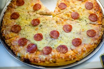 Pizza with salami and cheese is on the shop window in the store 