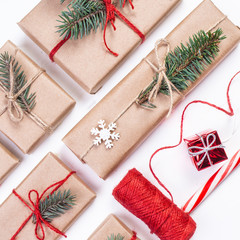 Festive boxes as Christmas present with ribbon bow and fir tree branch on white background wrapped in craft paper.