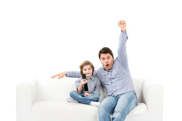 Happy family of two people, fans father and son on couch with a remote control from TV.