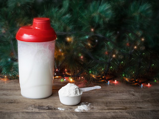 Whey protein shaker and scoop on christmas background. Sports nutrition