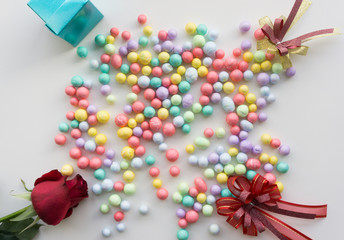 Top view blue gift box, ribbon, Colorful balls and red rose on white background.