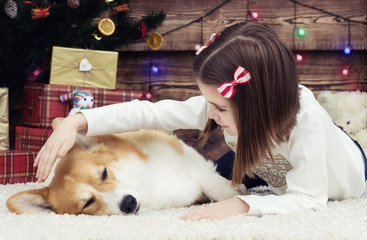 baby girl gently hugs a dog on the fluffy carpet