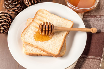 Honey with stick pouring over toast bread