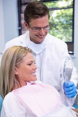 Fototapeta premium Dentist showing mirror to smiling patient