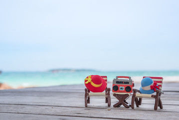 Naklejka premium Miniature radio on a table and beach chair with sea background.