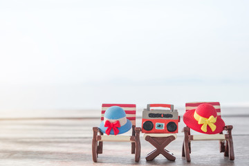 Miniature radio on a table and beach chair with sea background.