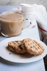 Grilled cheese wholegrain sandwich with tomato and cup of coffee with milk on light table background. Morninig concept
