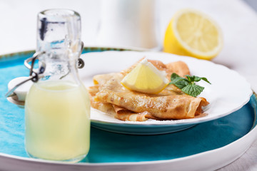 Lemon juice in bottle with pancakes on background