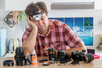 Amateur photographer is trying to repair his lens. A hobby amateur cleans the device of a digital...