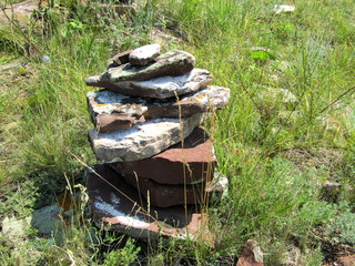 Folded flat stones on a rock on background grass