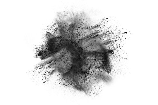 Black powder explosion against white background.The particles of charcoal splatted on white background. Closeup of black dust particles explode isolated on white background.