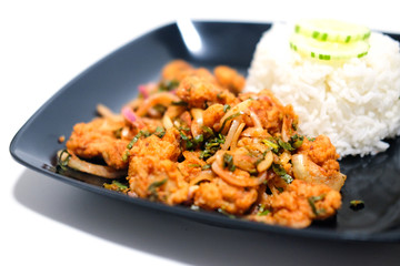 Spicy salad fried chicken with rice in black dish