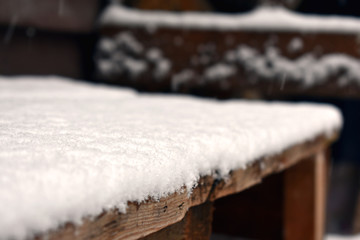 Fototapeta na wymiar The first white snow on the wooden construction table
