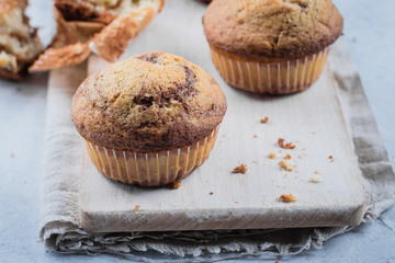 Homemade sweet chocolate vanilla muffins from two types of dough with glass and bottle of milk on wooden table background. Copy space