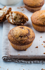 Homemade sweet chocolate vanilla muffins from two types of dough with mason jar of milk on on wooden board on blue stone table background