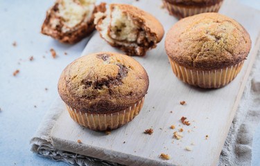 Homemade sweet chocolate vanilla muffins from two types of dough with mason jar of milk on on wooden board on blue stone table background