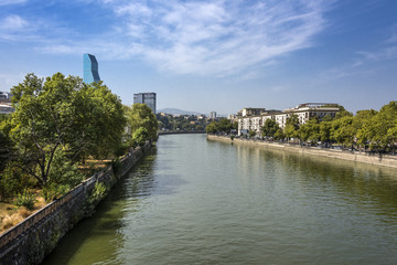 Fototapeta na wymiar Kingdom of Georgia, Tbilisi (Tiflis): Panorama of the Georgian capital with Kura river in the center and mountains at the horizon.