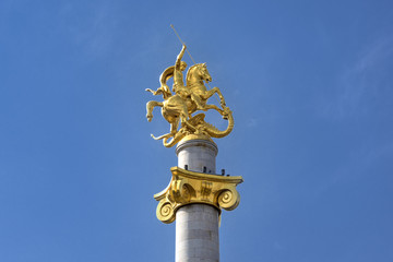 Fototapeta na wymiar Kingdom of Georgia, Tbilisi (Tiflis), near City Council: Statue of Saint George who stays the dragon in the center of the Georgian capital blue sky in the background.