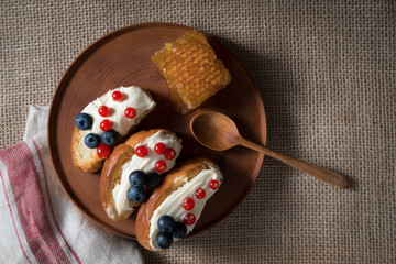 fried bread, toast with yoghurt and berries, bilberries, blueberries and red currants on a wooden plate with honey honeycomb
