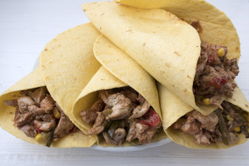 Fajitas consisting of chicken stew with red and green pepper, with red onion, pickled cucumber and spices wrapped in a corn cake.