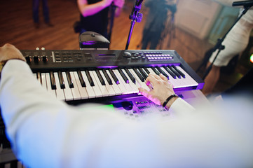 Hand of keyboardist on stage with lights.