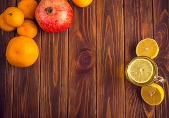 Tea with lemon on a wooden table with citrus fruits, orange, mandarin and garat. Ingredients for a Christmas drink
