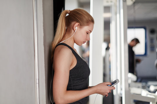 Junge Frau im Fitnesscenter mit Smartphone