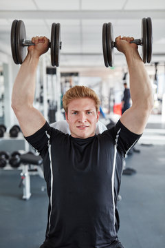 Junger Mann mit Kurzhanteln beim Bodybuilding