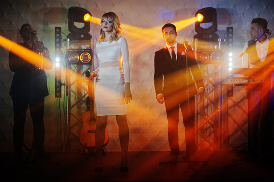 Musicial music live band performing on a stage with different lights.