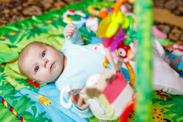 Cute adorable newborn baby playing on colorful toy gym