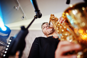 Musicial music live band performing on a stage with different lights. Saxophonist plays.