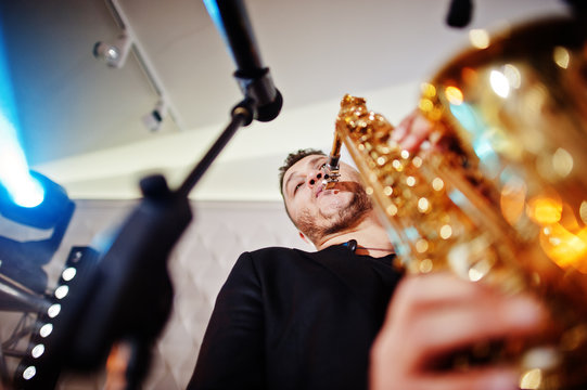Musicial music live band performing on a stage with different lights. Saxophonist plays.