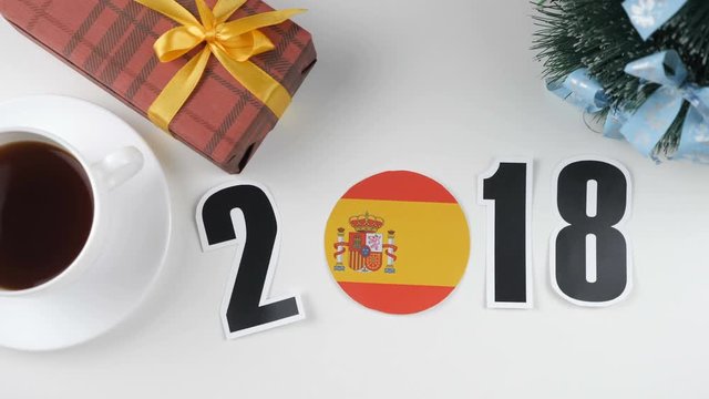 Illustration, new year, male hand put on the table an Spain flag, cauntry ball, 2018