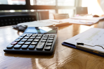 Calculator with report paper and office supplies on desk